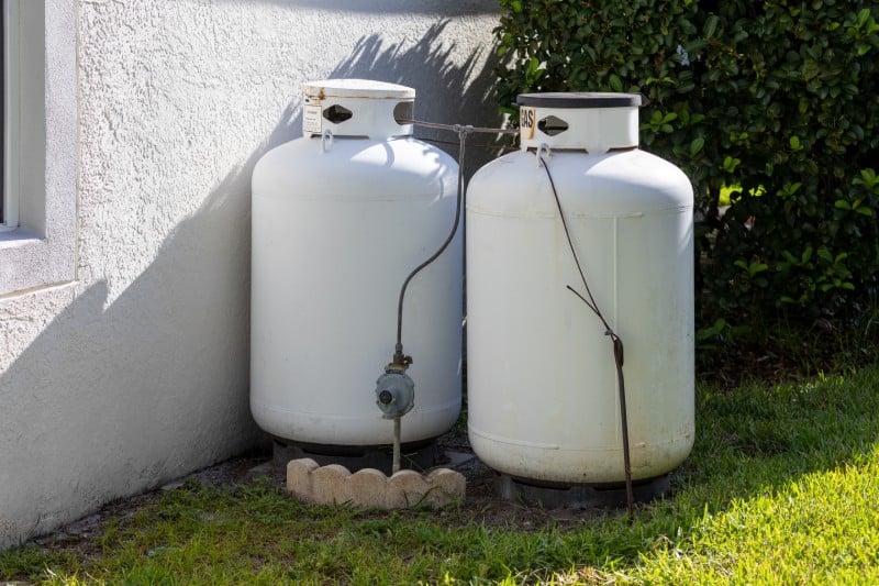 Two large white propane tanks located on the side of a home.