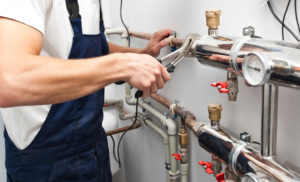A plumber from Henrico, VA checks the pipes of a home heating system.
